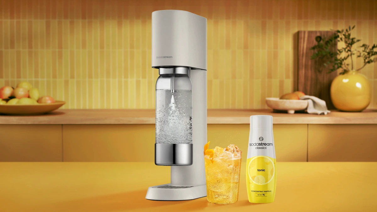 Saturator Sodastream Enso stoi na blacie kuchennym. Obok, syrop Sodastream Tonic oraz szklanka z gotowym napojem gazowanym.